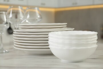 Poster - Clean plates, bowls and glasses on white marble table in kitchen