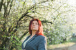 © satura_ - Beautiful red-haired woman enjoying smell in a flowering blooming spring garden. Spring blossom. Copy space