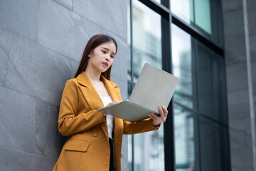 businesswoman - Successful business woman working with laptop computer standing near office building. City businesswoman working