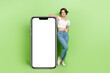 © deagreez - Full body portrait of nice cheerful lady showing big empty space smart phone display ad isolated on green color background