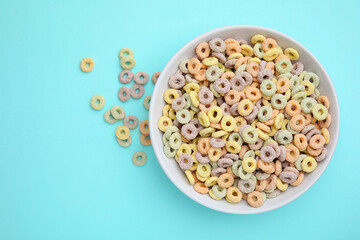 Wall Mural - Tasty cereal rings in bowl on light blue table, top view. Space for text