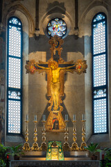 Wall Mural - Medieval fresco of crucifix decorating wall behind altar with golden candlesticks inside ancient italian church