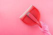 Hand in pink rubber glove holding dustpan and brush