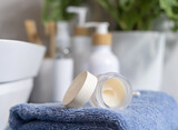 Fototapeta Boho - Opened lip balm jar near personal care products on blue towel close up, cosmetic mockup
