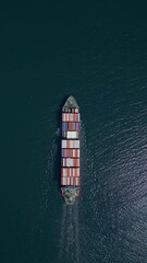 Wall Mural - A container ship moves steadily through the ocean, carrying stacked containers