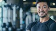 Fit Asian Man in Gym Attire. A portrait illustrating fitness and well-being with a confident grin in a sports setting.