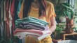 Softness of Asian young woman holding and folding clean clothes at home