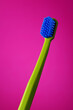 Green and blue toothbrush isolated on pink background