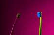 Green and pink toothbrushes on vibrant pink