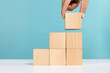 Concept for business growth or success process. Hand put last piece of wooden cube stacking as step stair