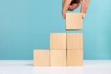 Fototapeta  - Concept for business growth or success process. Hand put last piece of wooden cube stacking as step stair