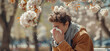 © anatoliycherkas - Young man with seasonal allergy in blossoming garden at springtime. Spring allergy concept.