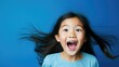 Cheerful Asian Kid Expressing Joy Against Vibrant Blue Background