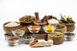Assortment of spices in glassware and wooden utensils close-up isolated on white background.