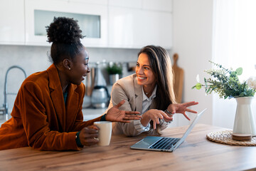 Wall Mural - Happy confident businesswomen video calling on laptop, working from home. Smiling female entrepreneurs talking by conference online virtual chat using laptop computer at home office sitting at desk.