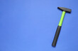 New hammer with rubber handle on blue background, top view. Space for text