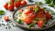   A plate of spaghetti topped with tomatoes, basil, and pepper sits on the table Tomatoes and basil are arranged beside it