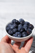 fresh blueberries in a white bowl in hand, vertical