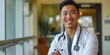 © HealthyStock - Content Asian male doctor with joyful expression, bright hospital interior.