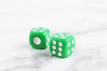 Two green game dices on white marble table, closeup