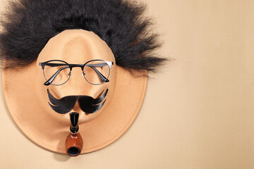 Sticker - Man's face made of artificial hair, mustache, glasses and hat on beige background, top view. Space for text