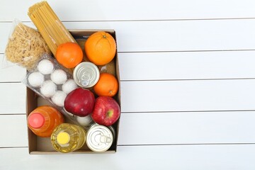 Wall Mural - Humanitarian aid. Different food products for donation in box on white wooden table, top view. Space for text