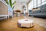 Fototapeta  - Robotic vacuum cleaner cleaning wooden floor in living room
