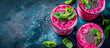 A fresh dragon fruit smoothie with chia seeds, fresh mint leaves and pink dragon fruits on a dark blue background, top view.