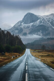 Fototapeta Na sufit - Empty road leading towards mountains under a dynamic sky. Beautiful landscape with highway and mountain ranges