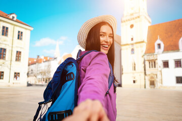 Adventurous millennial lady exploring city, holding cameraman hand