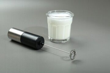 Sticker - Mini mixer (milk frother) and whipped milk in glass on grey background