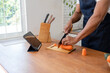 A person chopping carrots on a wooden table.