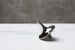 One metal spinning top on white table, closeup. Space for text