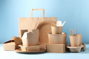 Wall Mural - Eco friendly food packaging. Paper containers, tableware and bag on white table against light blue background