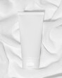 Empty white plastic tube for cosmetics on a towel. Mockup. Packaging for cream, gel, serum