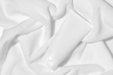 Wall Mural - Empty white plastic tube for cosmetics on a towel. Mockup. Packaging for cream, gel, serum