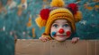Cheerful Child in Clown Costume Peeking Behind Blank Cardboard Banner on Festive 1 April Fool's Day