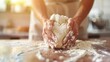 Hands kneading dough on a wooden surface with flour dust. Close-up of baking process with natural sunlight. Homemade baking and cooking concept.