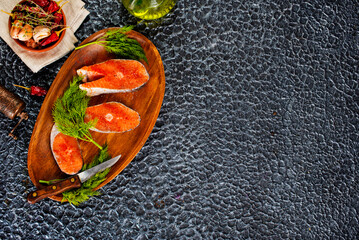 Sticker - fresh salmon steak raw fish prepared for cooking. Top view on black slate table.