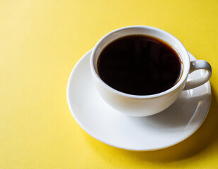 Wall Mural - A cup of black coffee on a yellow background.