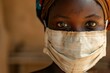 Close-up portrait of an African girl wearing a medical mask looking at the camera against a background in a poor village