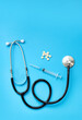 Stethoscope, pills and syringe on a blue background, top view. Cardiology and healthcare concept. Auscultation device. Medical care concept. Medical instrument. Auscultation apparatus