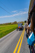 A view from a tour wagon captures an Amish buggy traveling down a rural road in Lancaster, PA, showcasing Amish transportation and the picturesque countryside. High quality photo. US