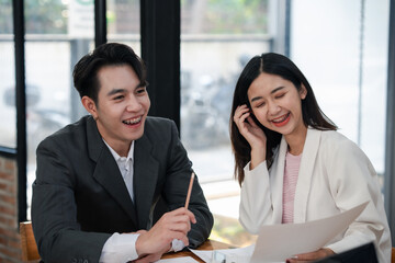 Smiling businessman and businesswoman discussing papers in a meeting with a laptop. Communication in workplace concept