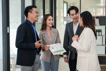 Business colleagues having a casual conversation in the office hallway. Candid workplace interaction. Networking and communication concept