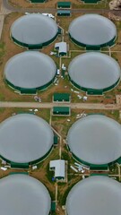 Wall Mural - Modern biogas plant on field. Flying over the storage tanks for biomass production. Environmentally friendly biogas plant. Top view. Vertical video