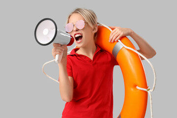 Wall Mural - Little boy lifeguard with ring buoy and megaphone on grey background