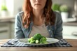 woman struggling with eating disorder small broccoli portion on plate concept photo