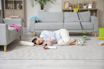 Poster - Tired young woman sleeping on floor after cleaning living room