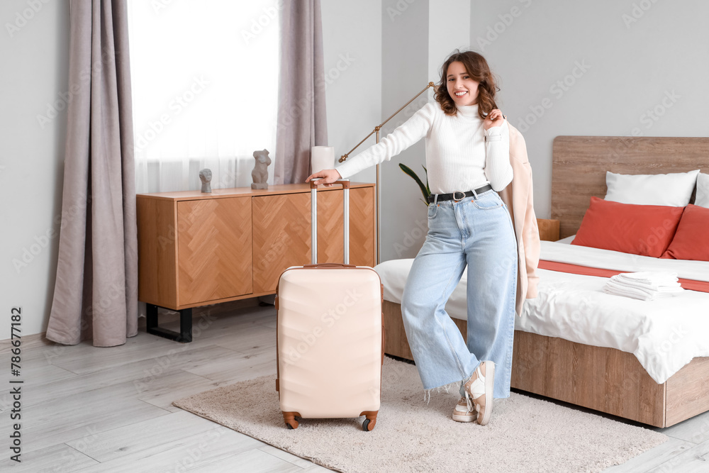 Female tourist with suitcase in hotel room